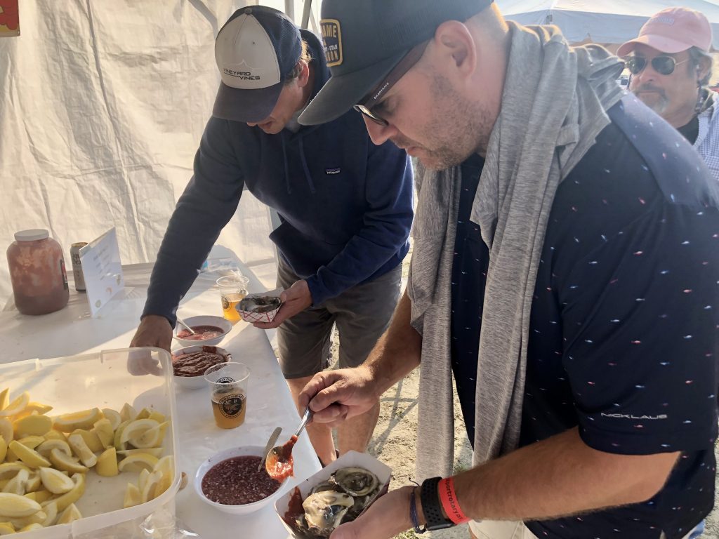 Billy Walsh of Weston, left, and Matt Malloy of Weston dress up their oysters with cocktail sauce and minced onions. / Photo by Thane Grauel
