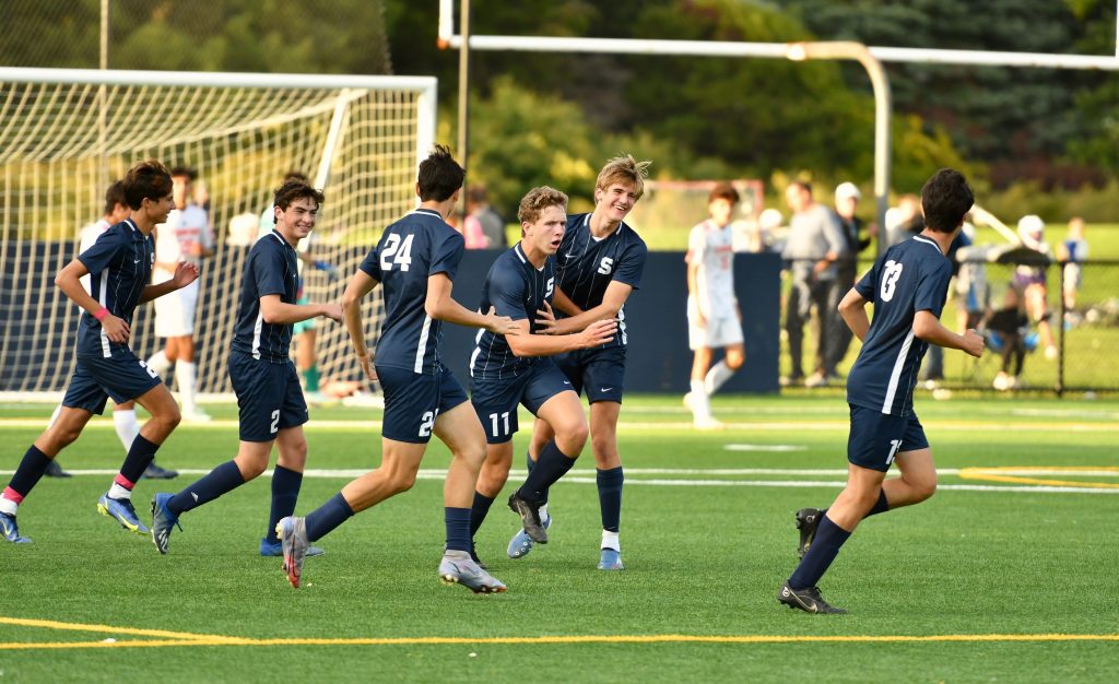 …. and celebrates with teammates. / Photo by Mark Sikorski