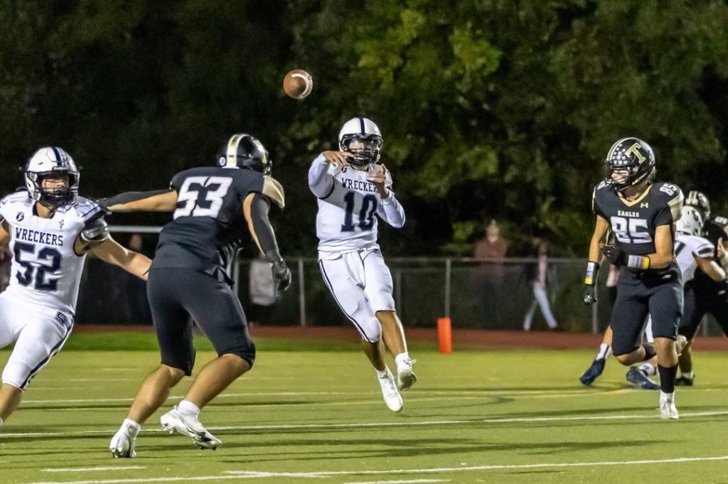Quarterback Caleb Smith throws a pass as Andrew Rossman (No. 52) blocks during the Wreckers' 36-29 win at Trumbull High on Friday night–Photo Chris Greer