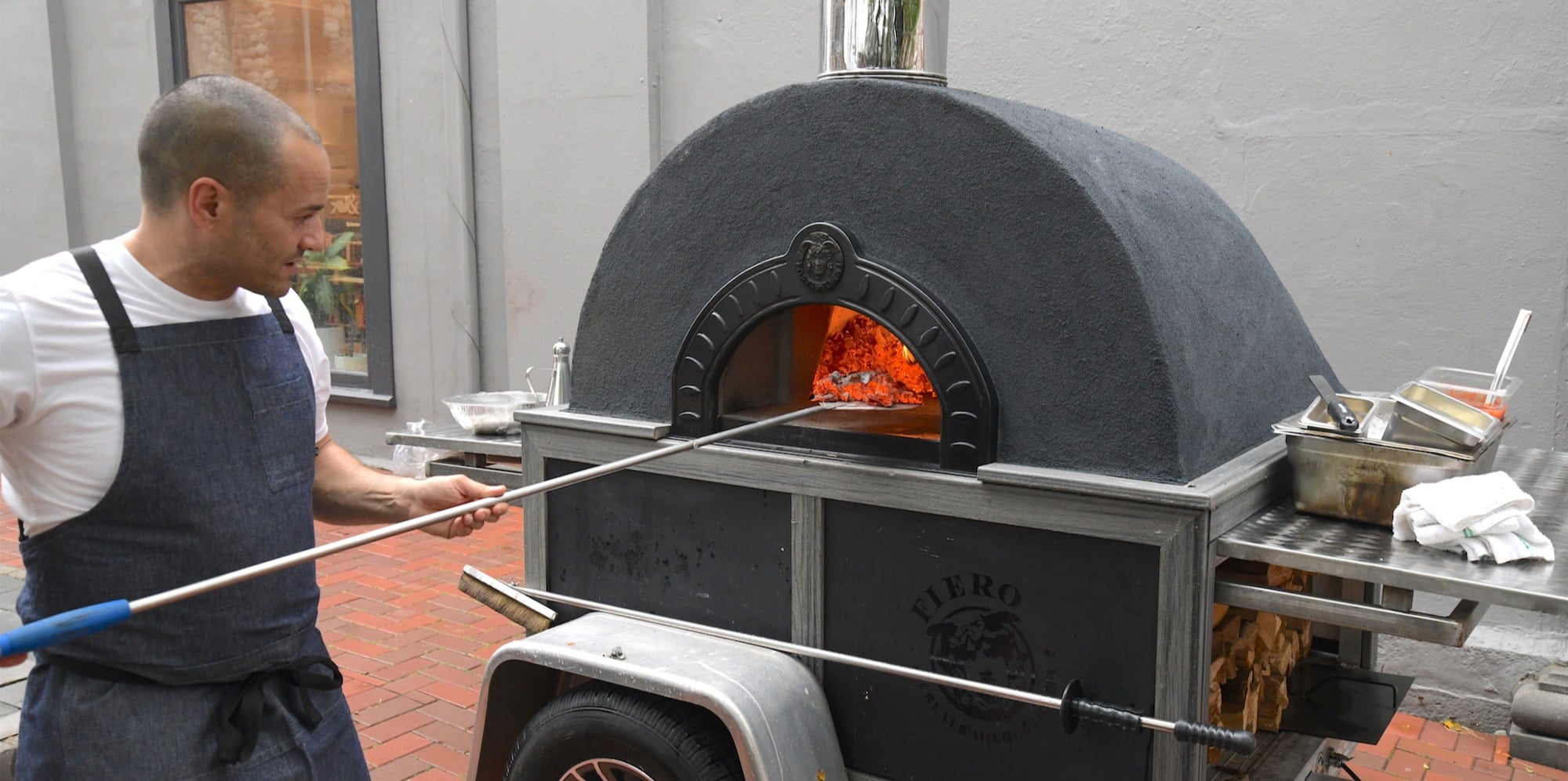 Owner Massimo Tulio works the outdoor pizza oven, rented for the occasion